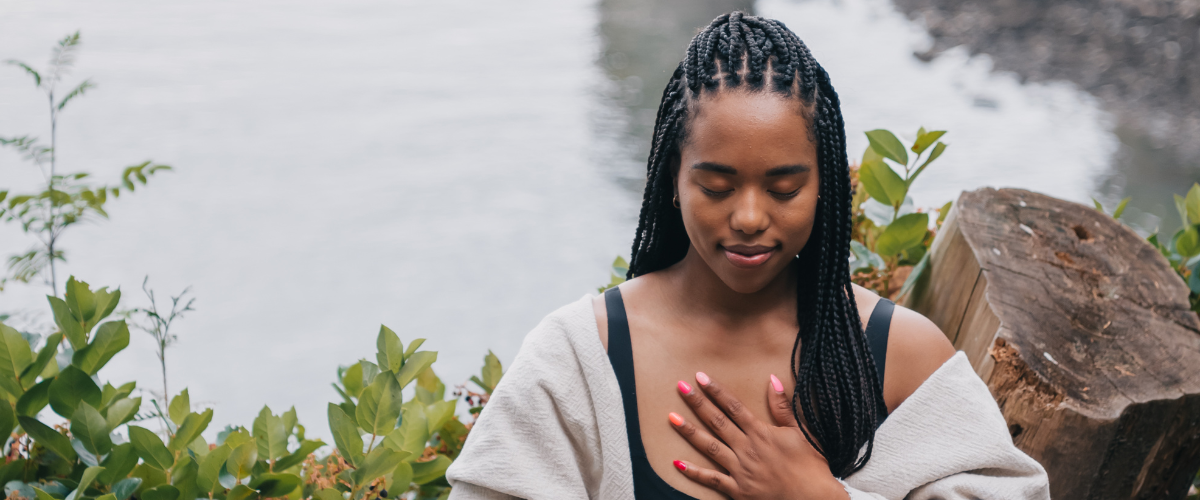 woman meditating by river during life coaching