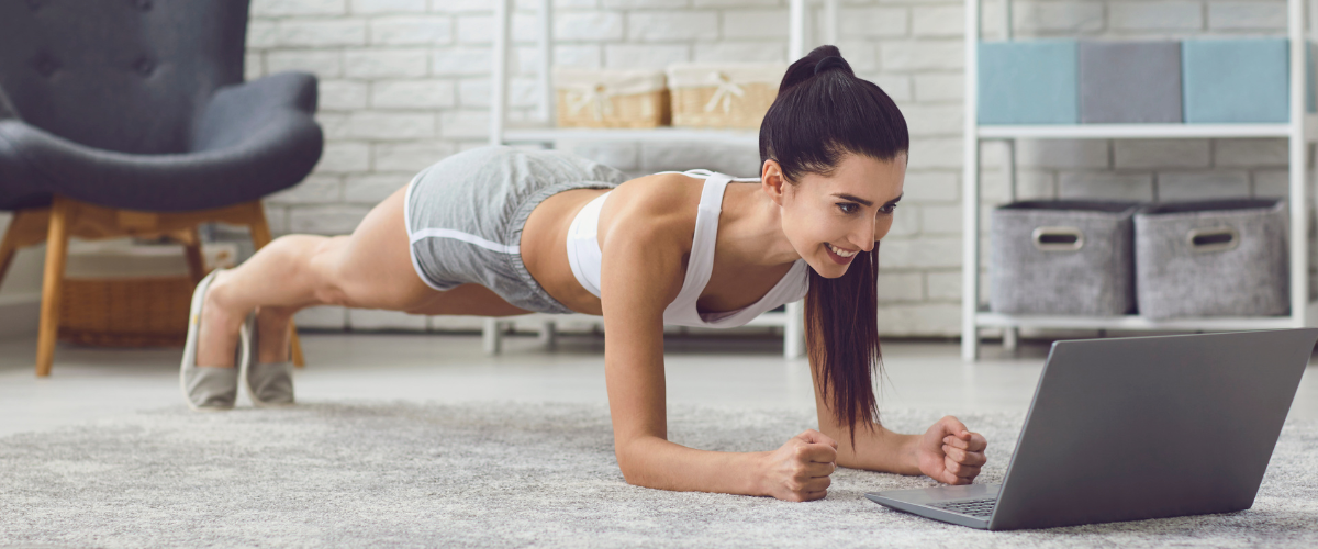 woman doing personal training at home on floor in front of laptop